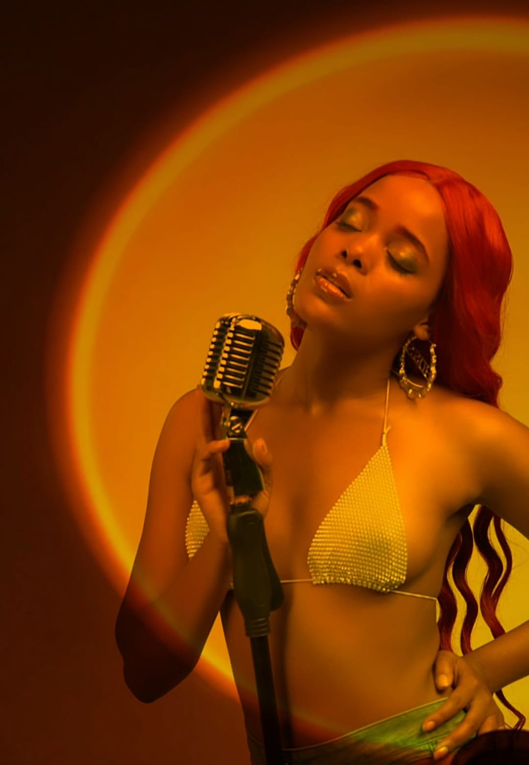AlxZandria singing into a vintage microphone under warm stage light